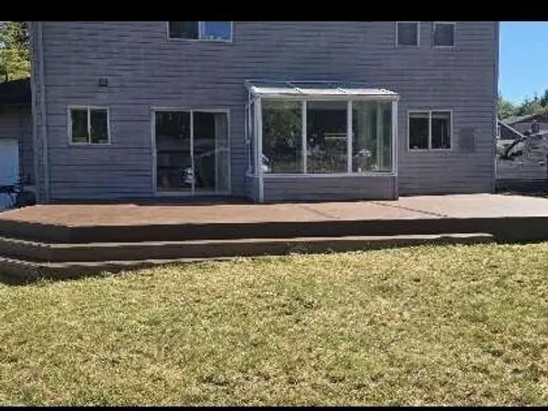 Wide new deck along the back of a gray two-story house