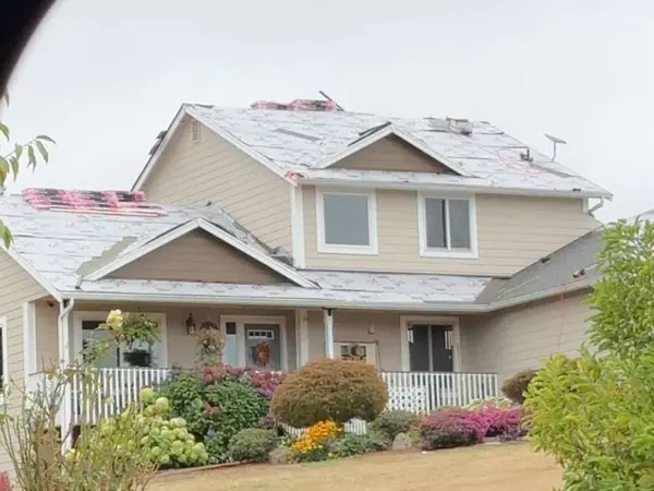 Two-story home during a roof tear-off, new shingles starting