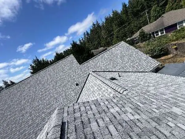 New gray shingle roof with valleys under a blue sky